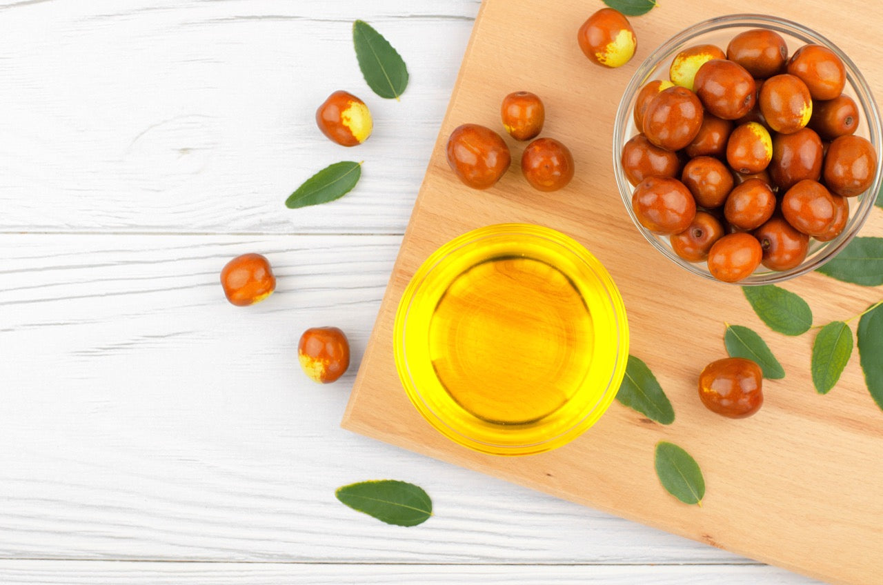 Jojobas on a chopping board and a cup of jojoba oil