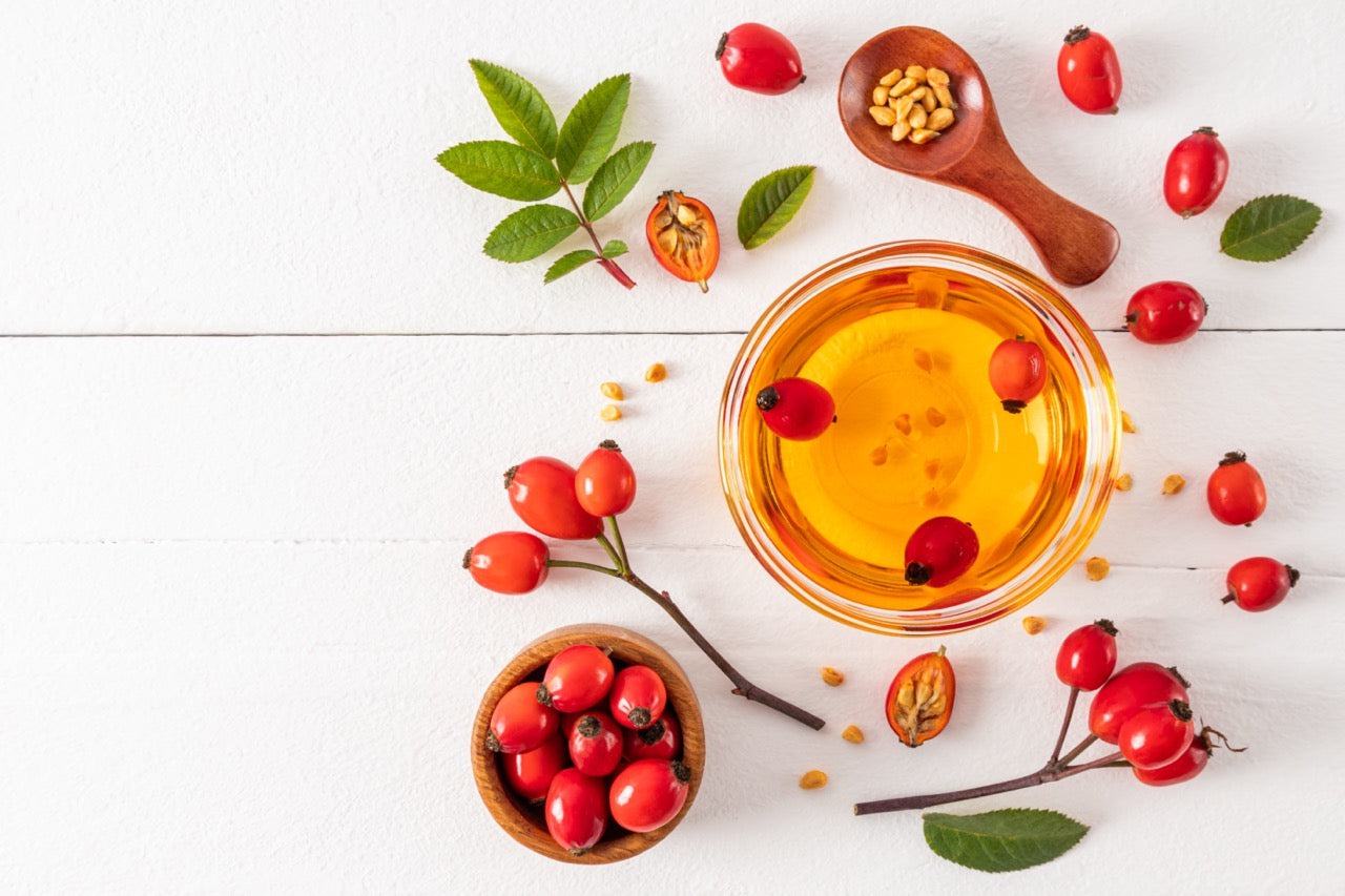 Rosehip oil and berries arranged on a white table